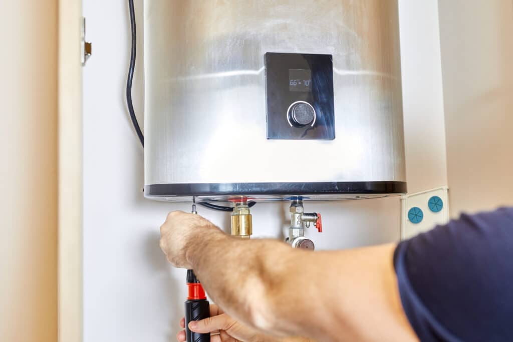 A technician tightens a pipe nut in the water heating system